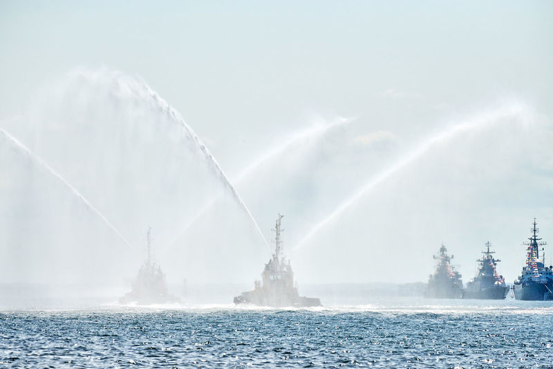 Floating tug boats spraying jets of water, demonstrating firefighting water cannons. fire boats