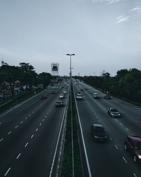 Vehicles on highway against sky in city