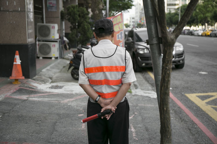 Rear view of traffic cop standing on street