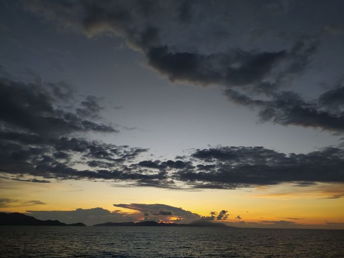 Scenic view of sea against dramatic sky during sunset