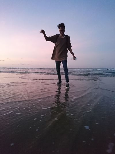 Full length of man standing on beach during sunset