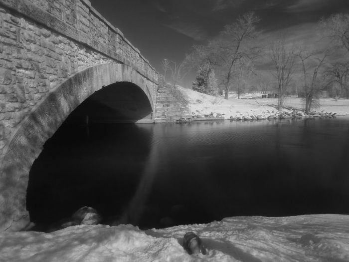 Arch bridge over river during winter