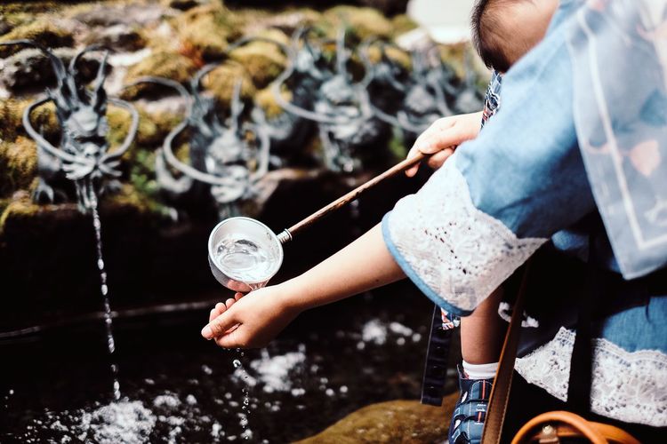 Midsection of woman pouring water from ladle