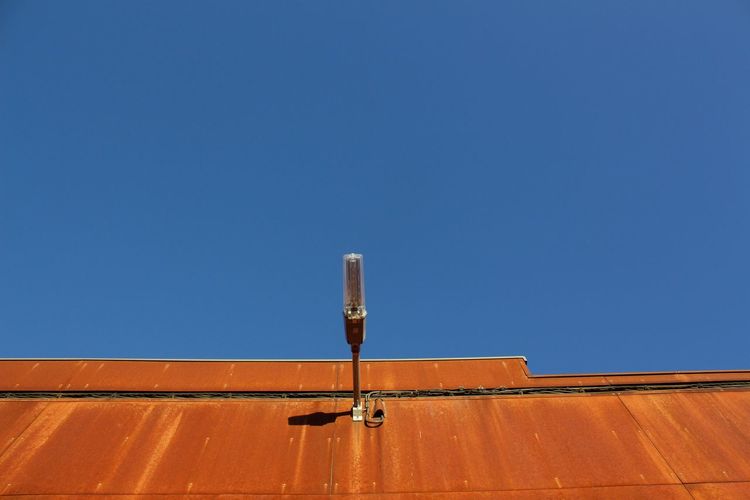 Low angle view of lighting equipment on building against clear blue sky