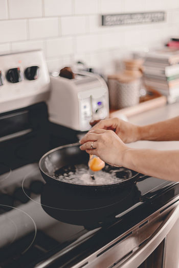 Midsection of person preparing food in kitchen at home