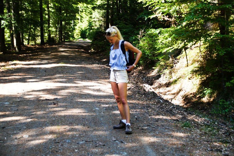 Full length of woman standing on pathway in forest