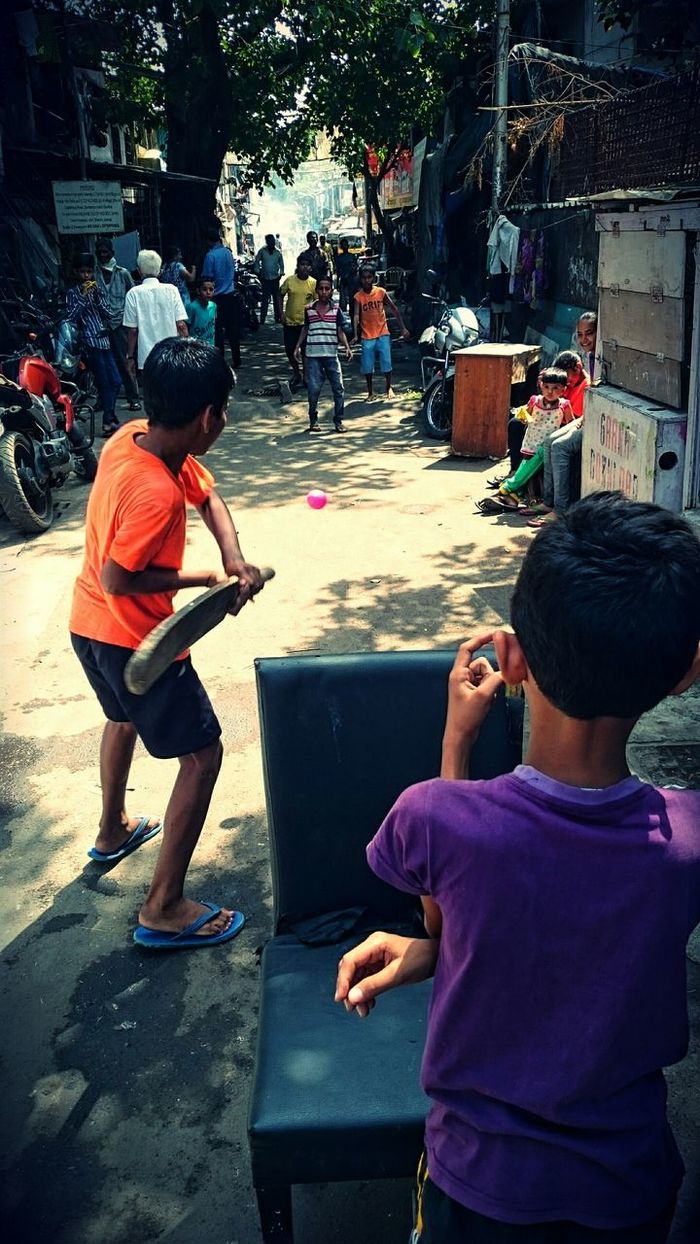 Boys playing cricket on street