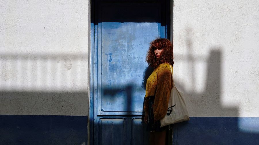 Woman standing by blue door