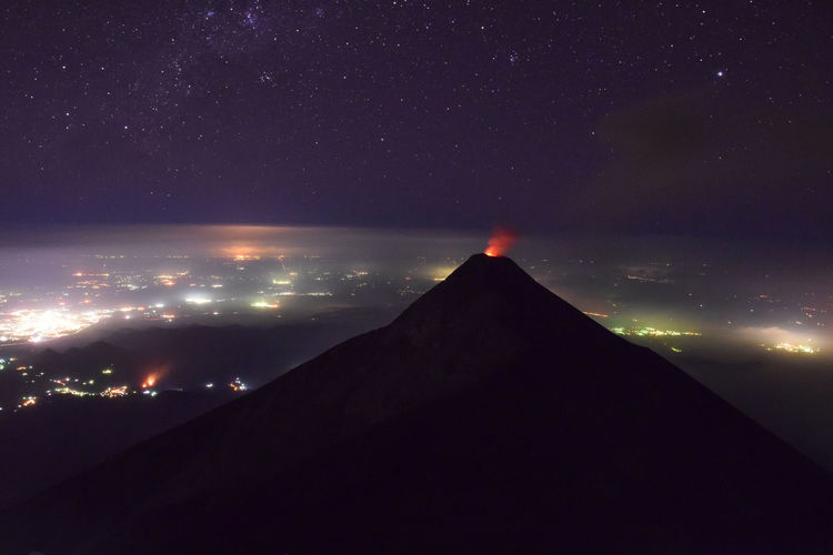 View of mountain and illuminated townscape against star field