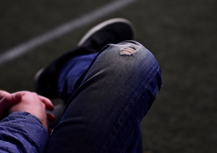 Low section of man wearing torn jeans while sitting outdoors