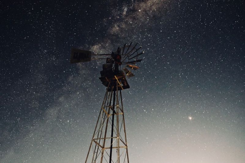 Low angle view of traditional windmill against star field at night