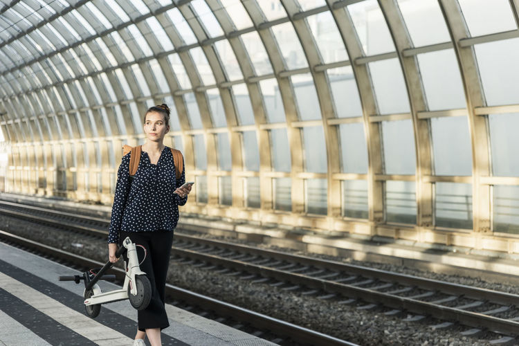 Young woman with electric scooter at the train station