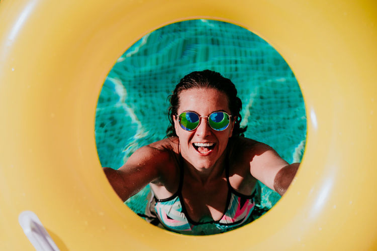 Portrait of smiling woman holding inflatable ring in swimming pool