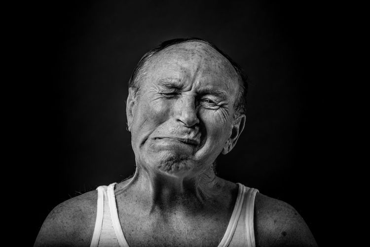 Close-up of man making a face against black background