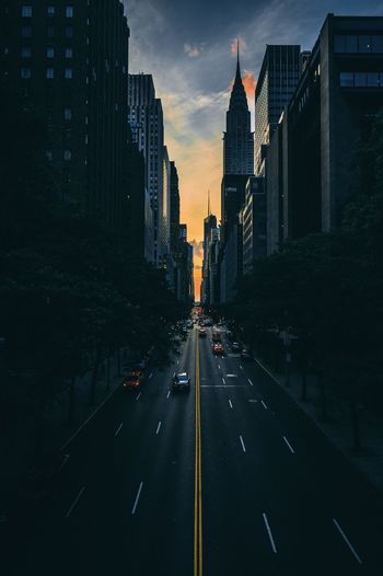 Road amidst buildings in city during sunset