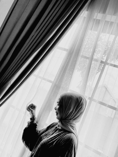 Woman in hijab standing by window