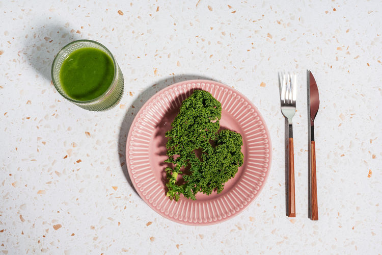 Green juice with kale on plate over terrazzo marble