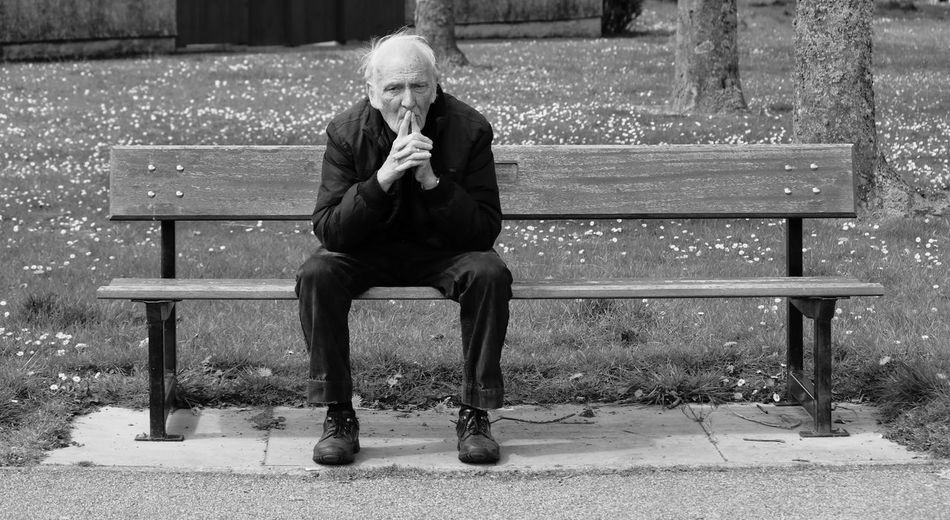Full length of senior man sitting on bench in park