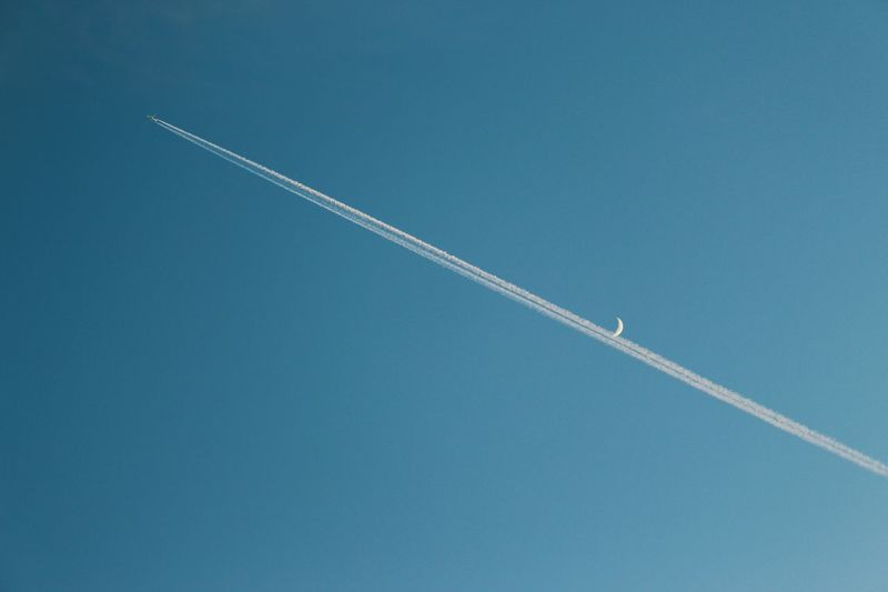 Low angle view aircraft flying against clear blue sky