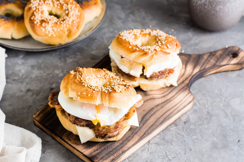 Bagels sandwiches with cheese, fried meat and poached egg on a board on the table. 