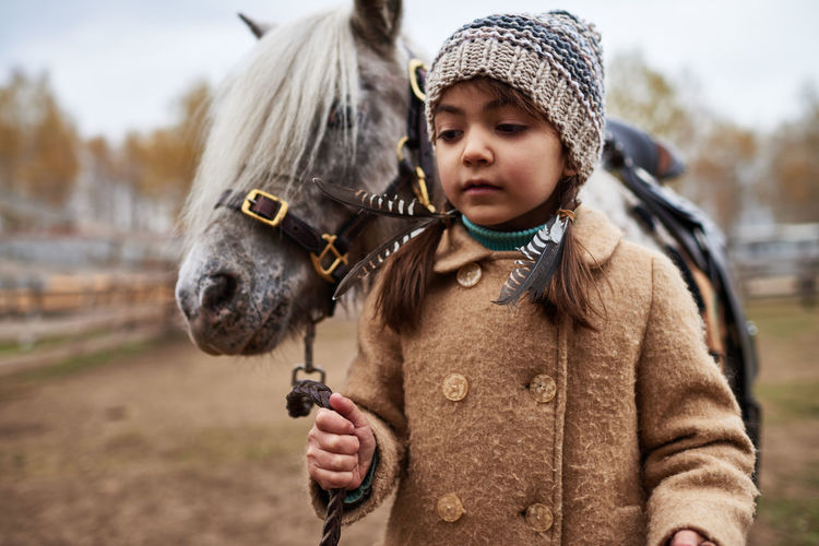 Pretty little girl leading pony by bridle