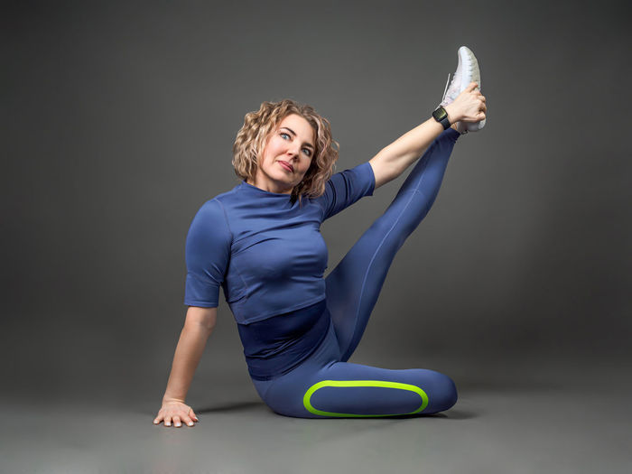 Portrait of young woman exercising against black background