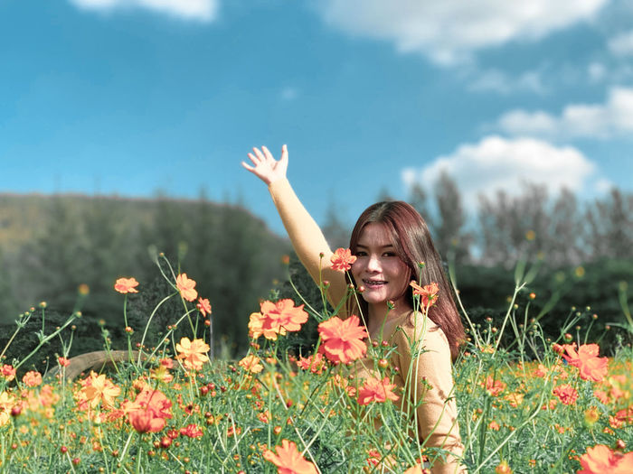 Portrait of happy woman with flowers on field