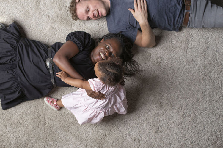 A young interracial couple playing with their young daughter