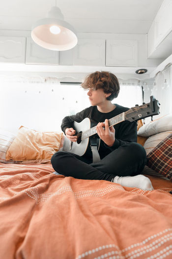 Young man playing the guitar in a camper van .