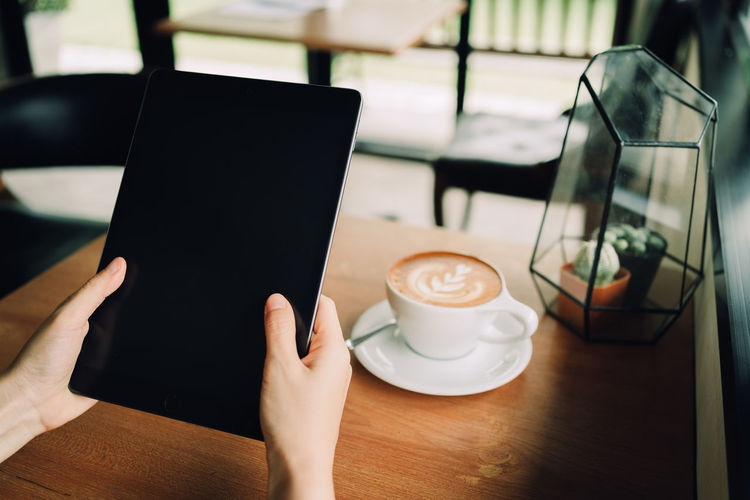 Hand holding coffee cup on table