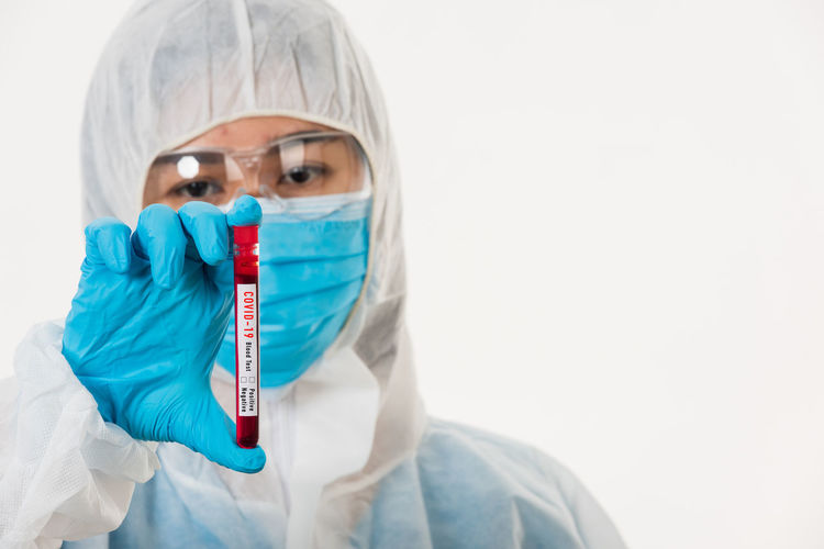 Portrait of doctor holding test tube against white background