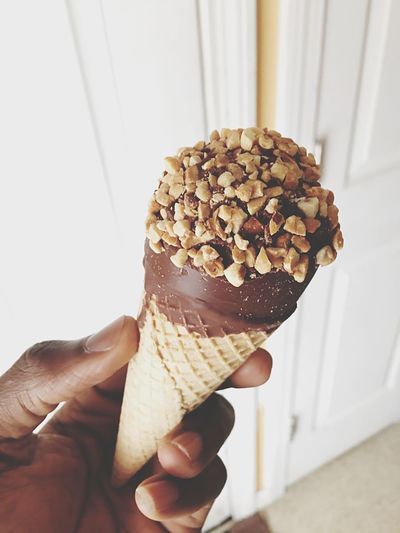 Cropped hand holding ice cream cone at home