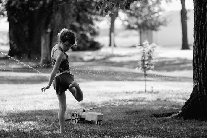 Girl playing with sprinkler water at park