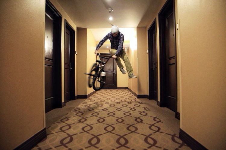 Man jumping mid-air on bmx bicycle in passageway
