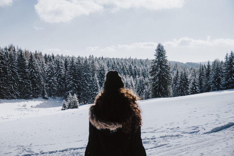 Rear view of woman standing on snow covered field