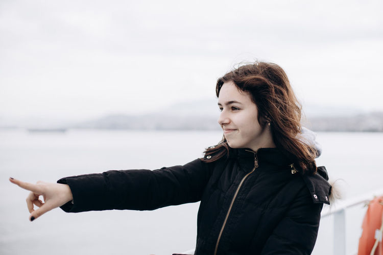 Smiling teenager girl on the ferryboat shows with finger to something