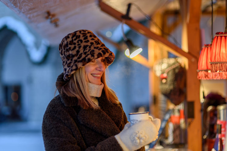 Smiling woman holding coffee cup at cafe during winter