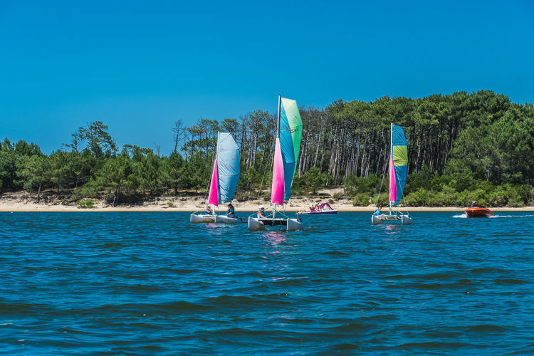 Sailboat in sea against clear blue sky
