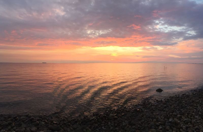 Scenic view of sea against dramatic sky during sunset