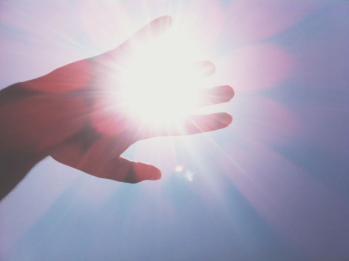 Close-up of hands against sun