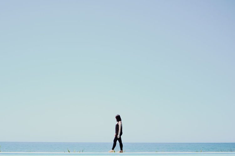 Side view of woman walking by sea