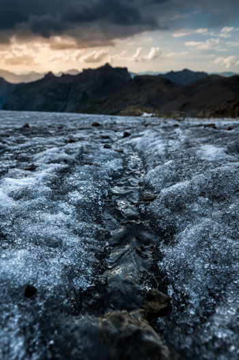 Frozen river against mountains during sunset