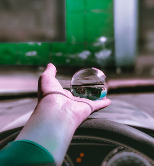 Cropped hand holding crystal ball on steering wheel in car