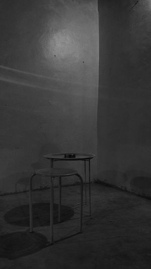 Empty chairs and table against wall in old building