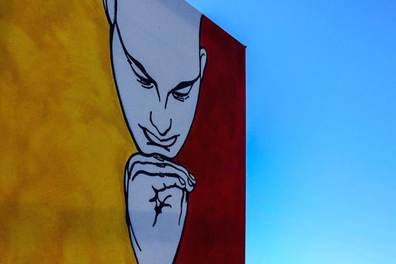 Close-up of graffiti on wall against blue sky
