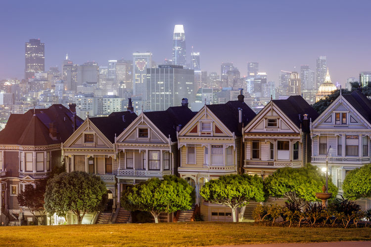 Dusk over the painted ladies. iconic victorian houses and san francisco skyline via alamo square,