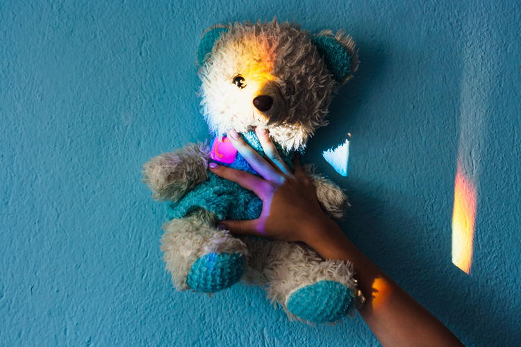 Portrait of baby girl holding toy against wall