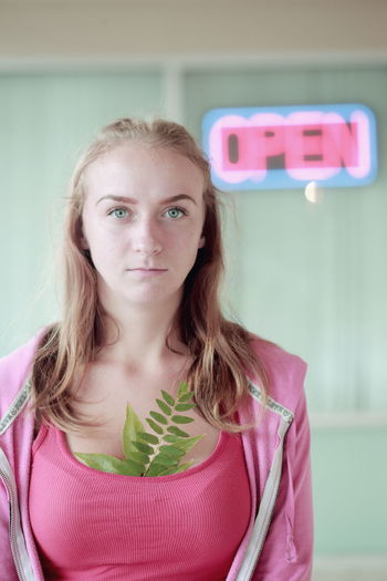 Portrait of young woman with leaves in tank top against open sign