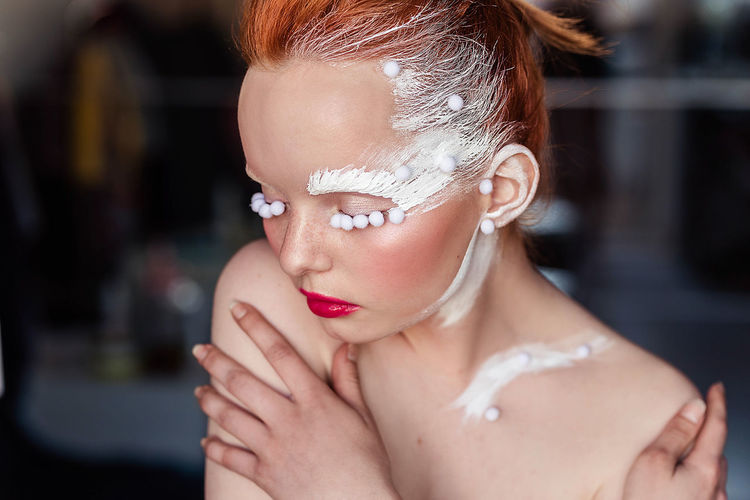 Close-up of young woman in white creative makeup 