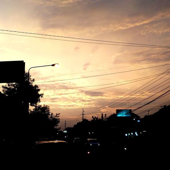 Silhouette street against sky at sunset